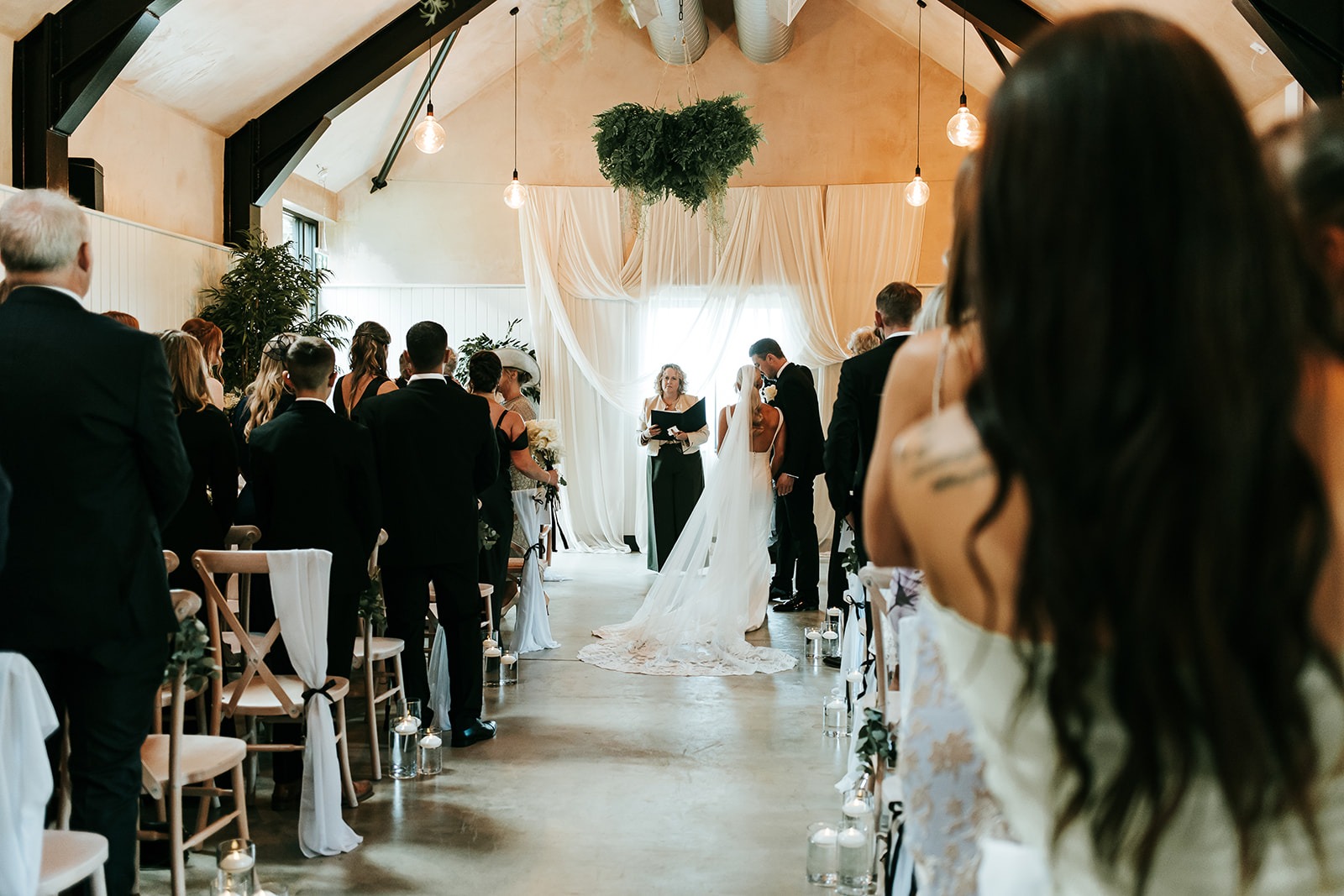 Wedding ceremony at Sandon Manor Wedding Venue with bride and groom standing before an officiant in a decorated venue